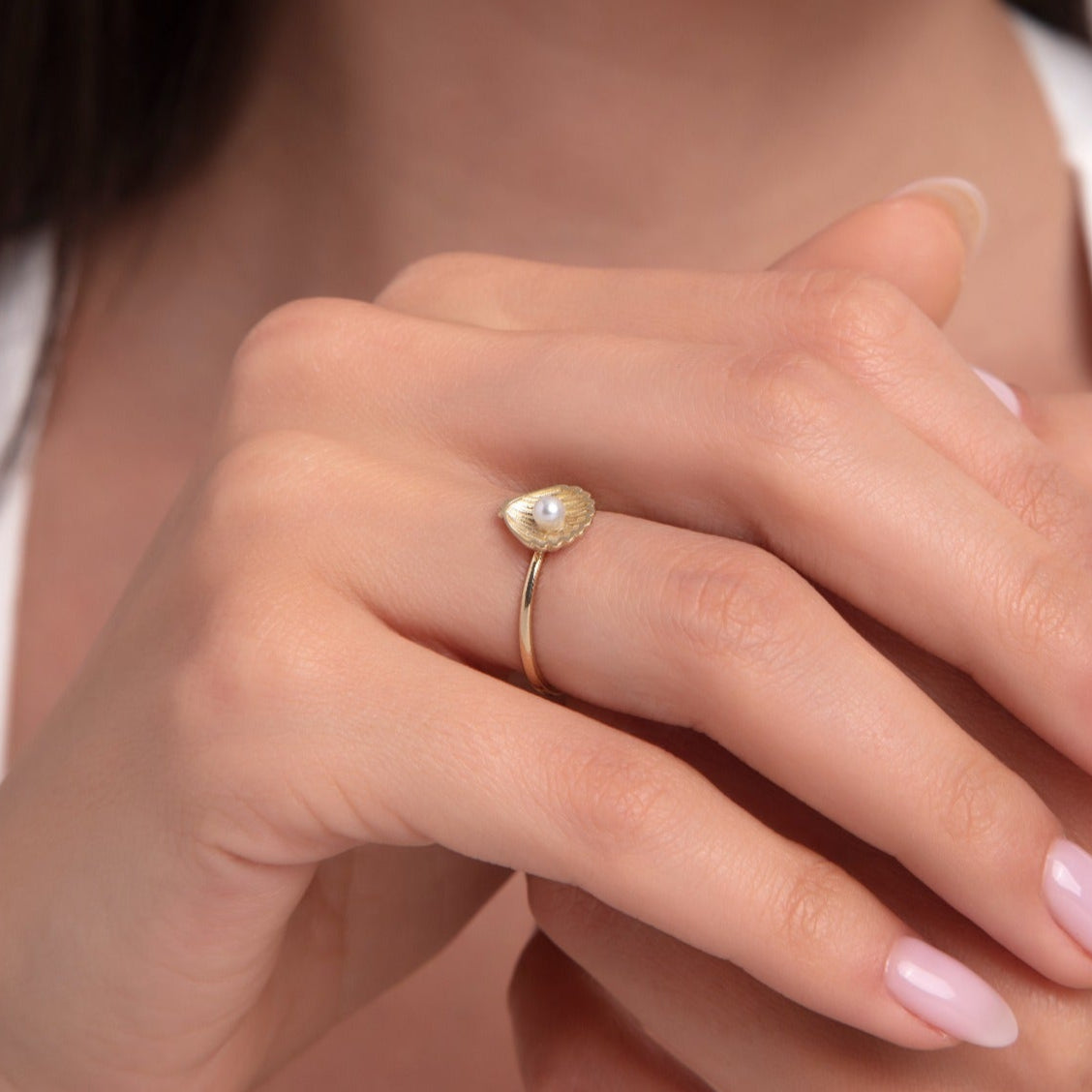 Close-up of 14K gold seashell ring with a centered pearl on hand, elegant and minimalist design